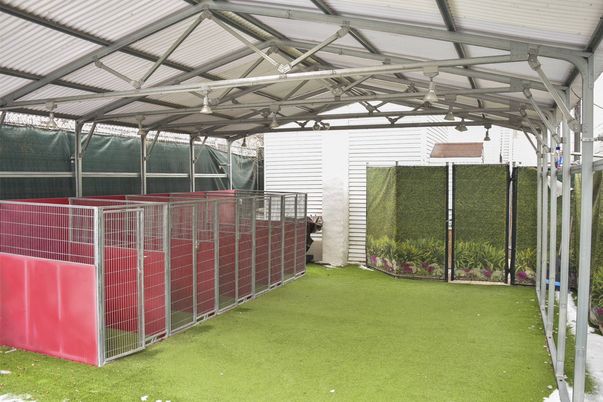 a covered area with a fence and a green wall<br />
